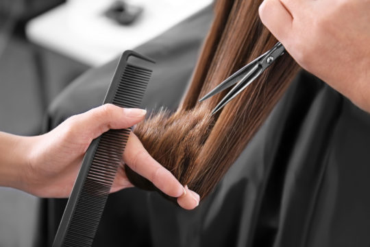 Professional stylist cutting woman’s hair in&nbsp;salon, closeup